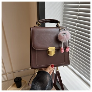 Dettaglio dello zaino in pelle marrone scuro con chiusura dorata e ciondolo di peluche