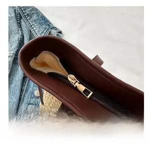Detail of high-quality gold metal zipper and brown leather trim on straw tote bag