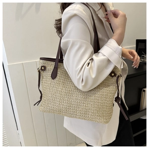 Detail of woven straw tote bag with brown leather straps and side knot decorative accents