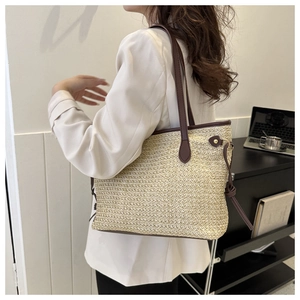 Detail of hand-woven straw tote bag with brown leather handles for summer travel