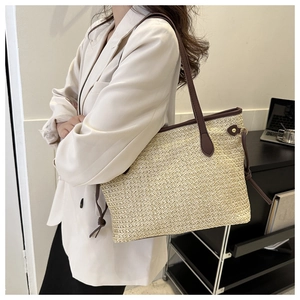 Detail of woven straw tote bag with brown leather handles in a chic office setting