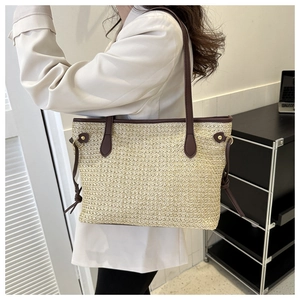 Detail of straw tote bag with brown leather handles and adjustable side drawstrings