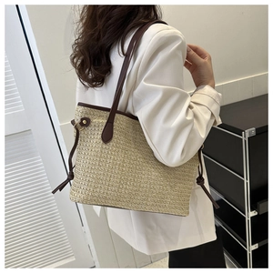 Detail of straw woven tote bag featuring beige texture and brown leather strap accents