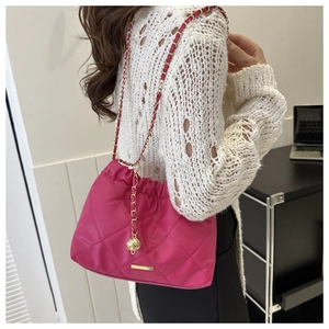 Detail view of fuchsia quilted shoulder bag with gold chain and sphere pendant charm
