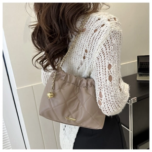 Detail of beige quilted shoulder bag with gold chain strap and drawstring design