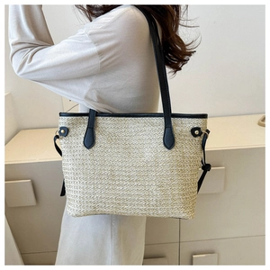 Detail of hand-woven straw tote bag with black leather shoulder straps and gold rivets