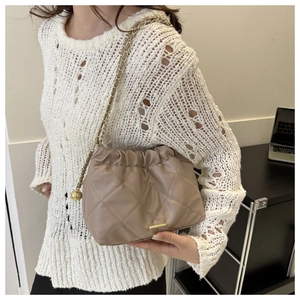 Quilted taupe crossbody bag with cloud pleats and gold chain strap on model