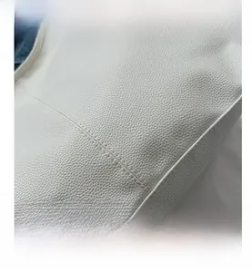 Close-up of white lychee pattern leather with neat stitching on a large tote bag