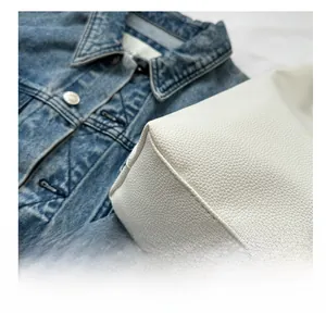 Close-up of white pebbled leather handbag showing detailed stitching and premium texture