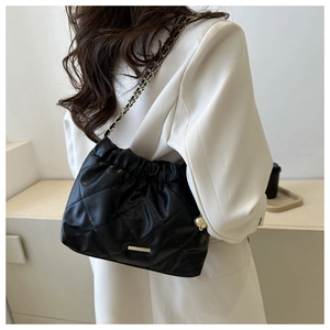Detail of black quilted chain shoulder bag with gold metal plate and cloud pleated closure