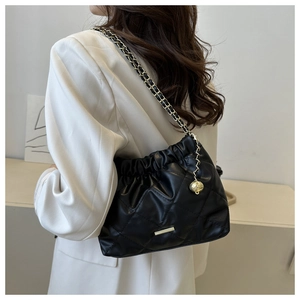 Detail of black quilted shoulder bag with gold chain strap and elegant pleated finish