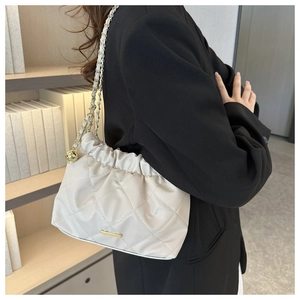 Detail of beige quilted shoulder bag featuring gold chain strap and elegant ruched design