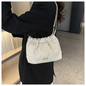Detail of a beige quilted shoulder bag with soft leather pleats and gold metal chain strap
