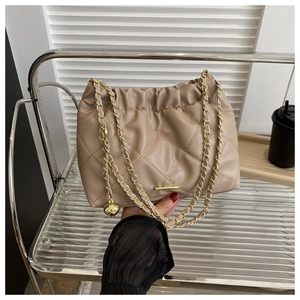 Detail of camel pleated shoulder bag with gold chain strap and metal charm on side