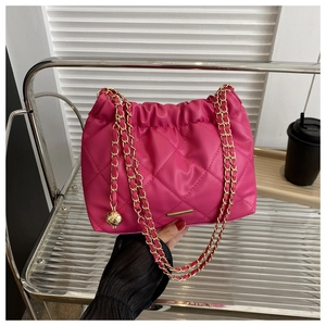 Detail of rose pink quilted PU leather shoulder bag with golden chain and ball charm