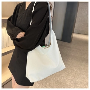Close-up of white PU leather tote bag with lychee texture on a model wearing a black dress