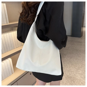 Detail of white large hobo bag with pebbled leather texture in a cozy bookstore setting
