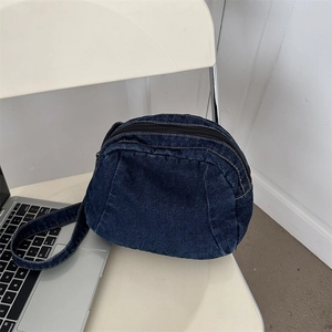 Retro deep blue denim crossbody bag in a round crescent shape on a white chair