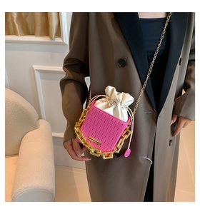 Detailed macro view of a pink mini bucket bag with gold chain and vertical pleats