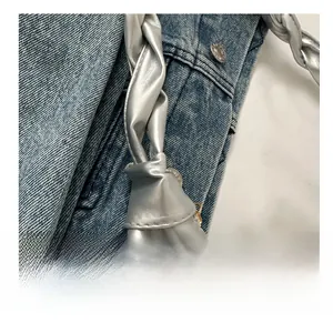 Close-up of a silver metallic tote bag featuring a chunky twisted rope handle design
