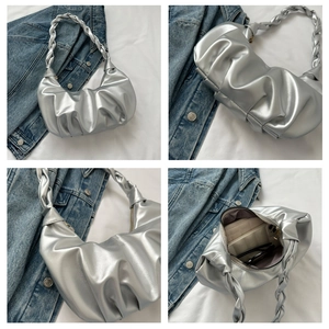 Close-up of silver metallic pleated handbag with woven handle and spacious interior