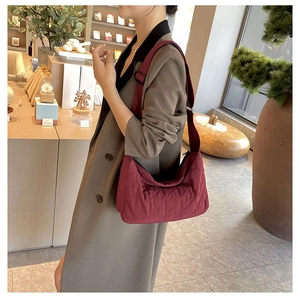 Macro detail of wine red quilted hobo bag featuring diamond stitching and wide strap
