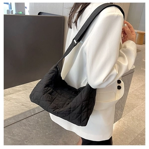 Detailed view of black quilted hobo bag with adjustable wide strap on white blazer