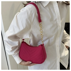 Detail of magenta quilted shoulder bag with elegant V-stitching and gold chain strap