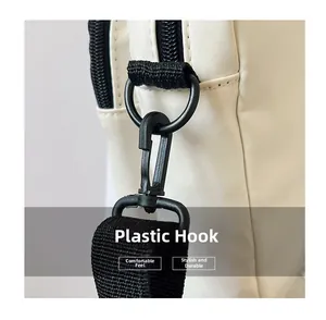 Detalle del gancho de plástico negro y el enganche de la correa en bolso de nailon blanco