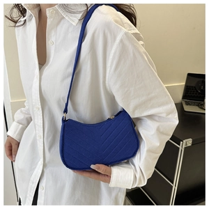 Close-up of dark blue chevron quilted velvet shoulder bag with golden zipper and strap