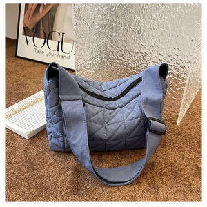 Detail of blue quilted pillow bag featuring diamond stitching and adjustable wide strap