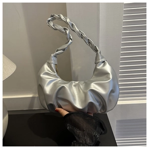 Close-up of a silver pleated crescent bag with a thick woven handle for women