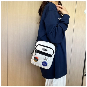 Detalle de bolso blanco para móvil con insignias de moda y correa negra ajustable al hombro