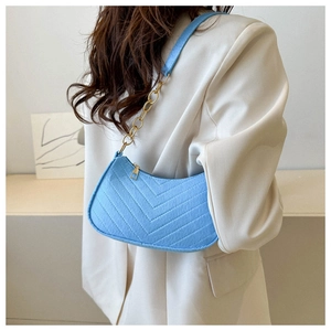 Detail of light blue crossbody bag with V-shaped quilting and gold metal chain strap