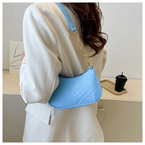 Close-up of light blue hobo bag with quilted texture and gold chain strap on shoulder