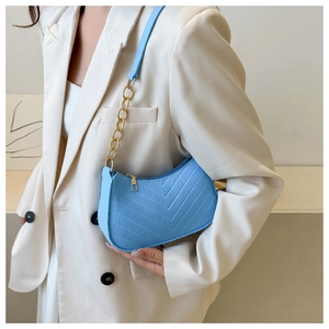 Close-up of sky blue crescent underarm bag with V-shaped quilting and gold chain strap
