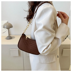 Detail of vintage brown shoulder bag featuring V-shaped quilting and gold chain strap