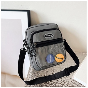 Detalle del bolso bandolera gris con ventana de PVC transparente e insignias de moda