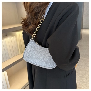 Close-up of grey felt shoulder bag with quilted texture and gold metal chain strap