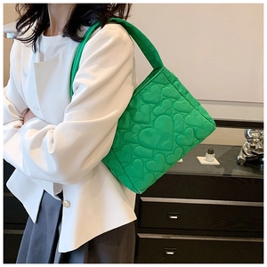 Groene gewatteerde nylon draagtas getoond op model met witte blazer en grijze rok