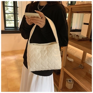 Detail van beige gewatteerde nylon shopper met hartpatroon en zachte gevoerde textuur
