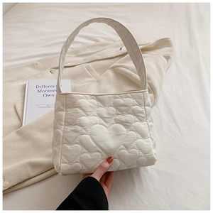 Detailopname van witte tote bag met hartvormig stiksel en gewatteerde nylon textuur