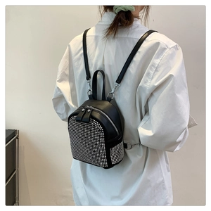 Detailed view of a mini black leather backpack with silver studs worn by a model