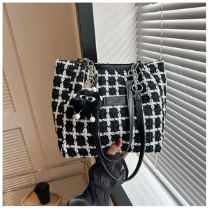 Detail of checkered tweed tote bag with metal chain strap and plush monster charm