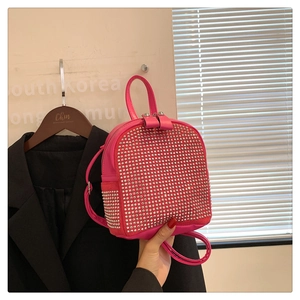Detailed view of magenta leather mini backpack featuring silver metallic stud embellishments