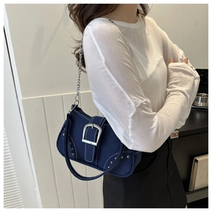 Detail of dark blue canvas bag featuring large silver buckles and metal rivet rows