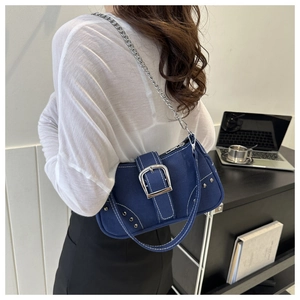 Detail of blue denim shoulder bag featuring bold silver buckle and chain strap