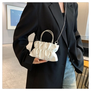 Detail of white ruched cloud bag featuring a sparkling rhinestone ring handle and chain