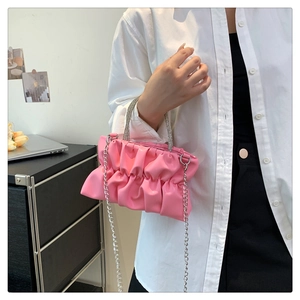Detailed view of pink pleated cloud bag with crystal handle and silver chain strap