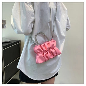 Detail view of pink pleated cloud bag with rhinestone round handle and silver chain